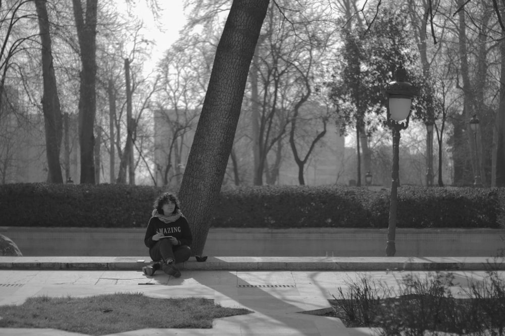 a person sitting on the ground next to a tree