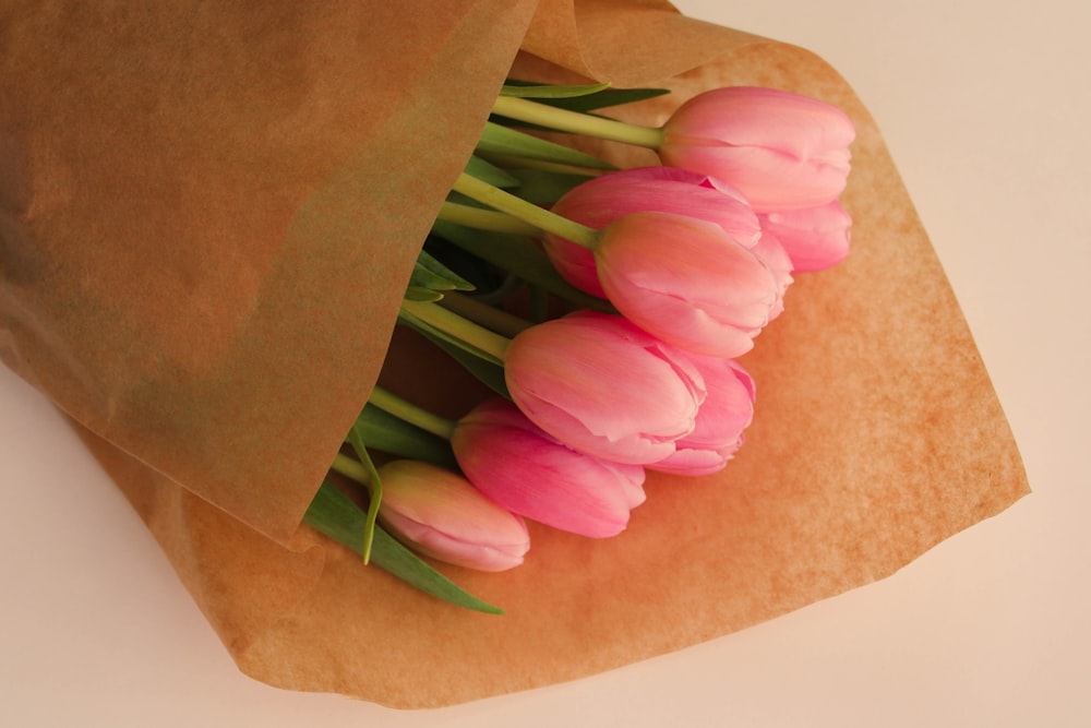 a bouquet of pink tulips wrapped in brown paper