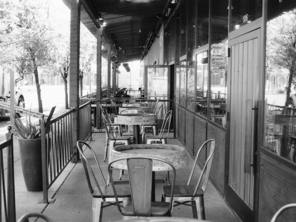 a black and white photo of tables and chairs on a porch