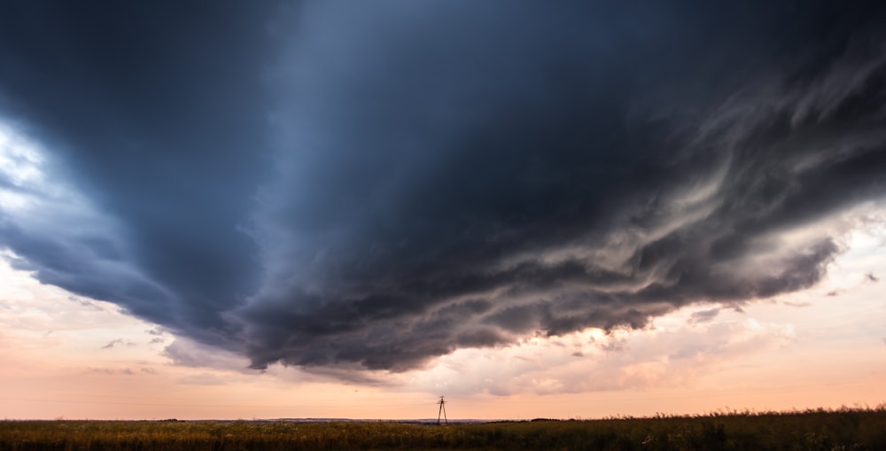 a large cloud is in the sky over a field