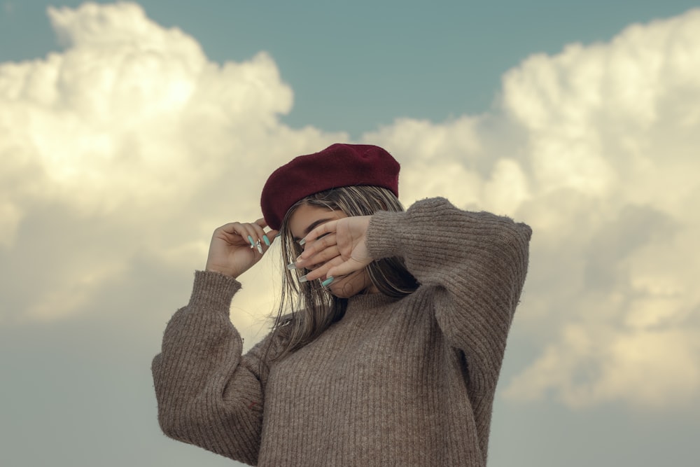 a woman wearing a red hat and a brown sweater