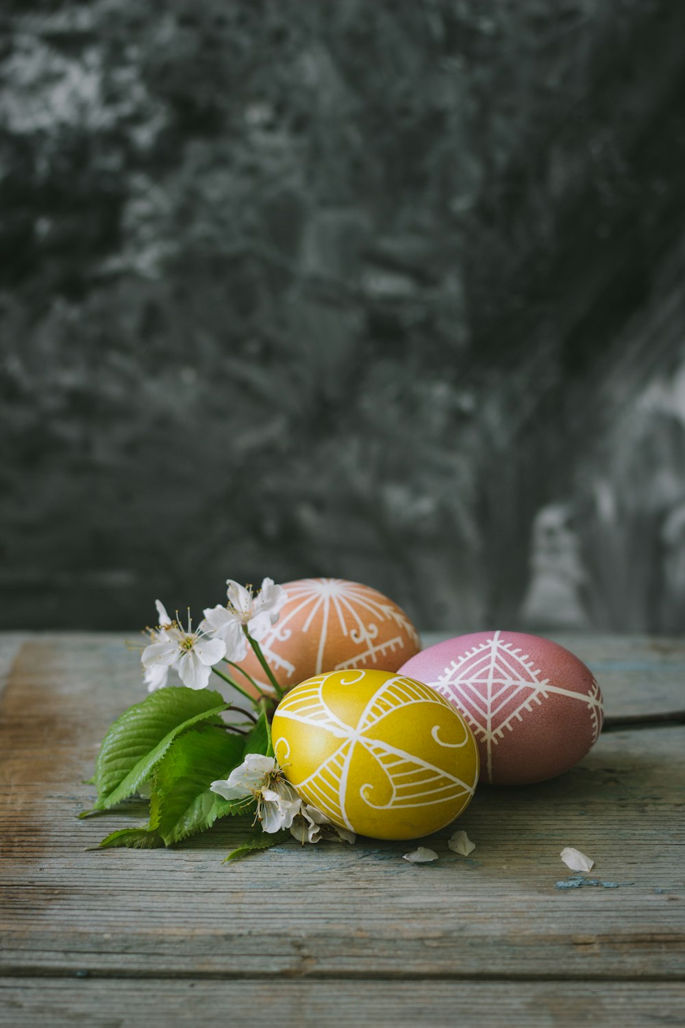 three decorated eggs sitting on top of a wooden table