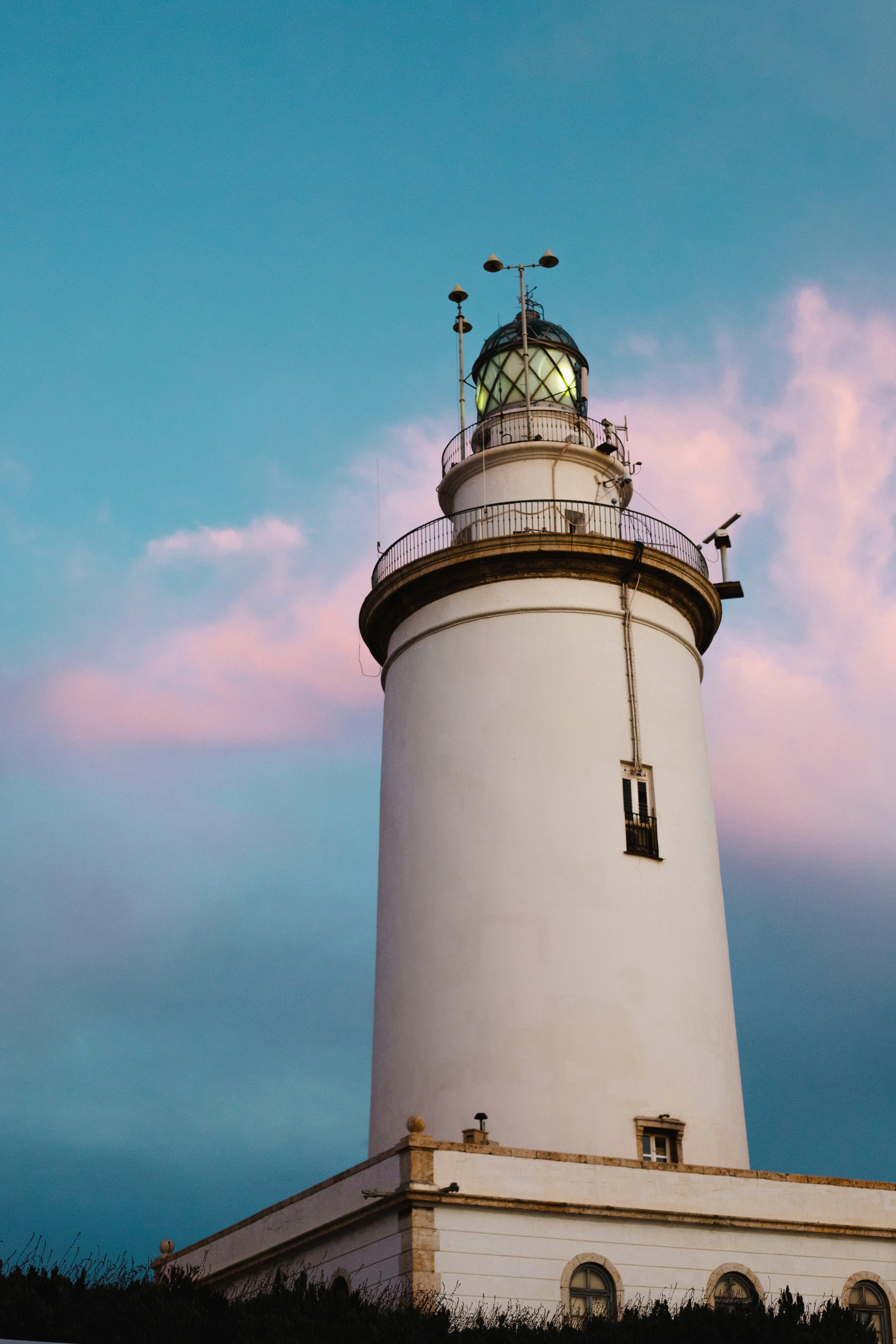 a white light house sitting on top of a hill