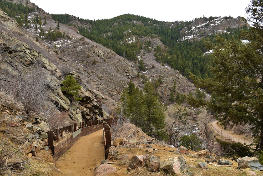 a dirt path with a wooden fence on the side of a mountain