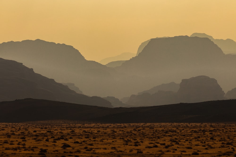 a mountain range is silhouetted against a hazy sky