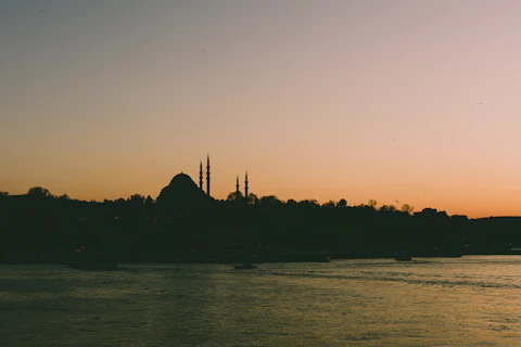A serene sunset behind a mosque silhouette with a glowing Qiblah compass overlay.