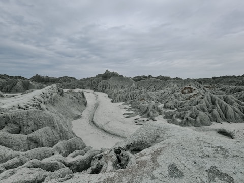 A vast alien landscape under a glowing purple sky with floating debris.