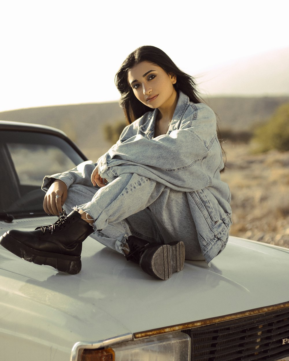 a woman sitting on the hood of a car