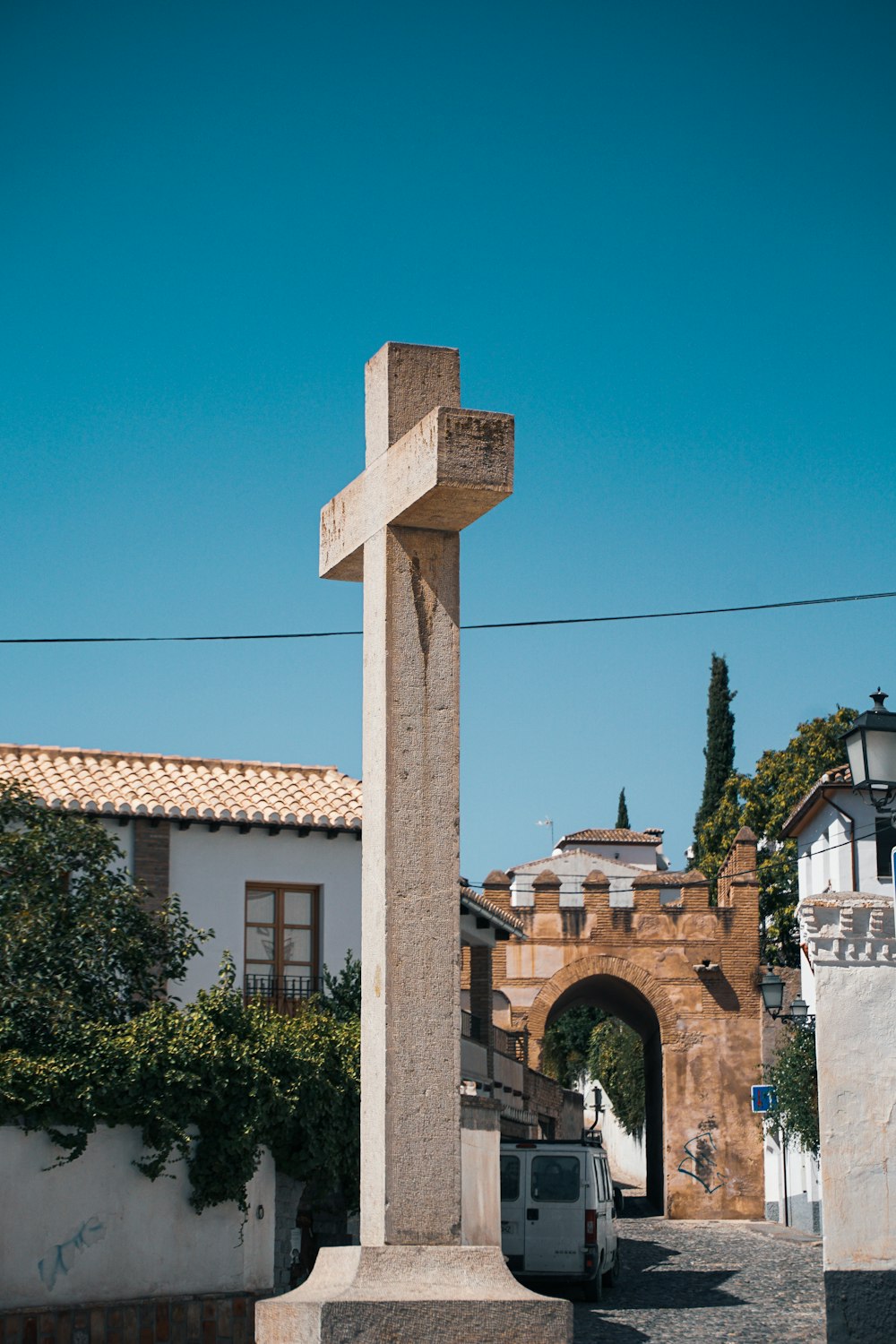 a cross on a stone pillar in the middle of a street