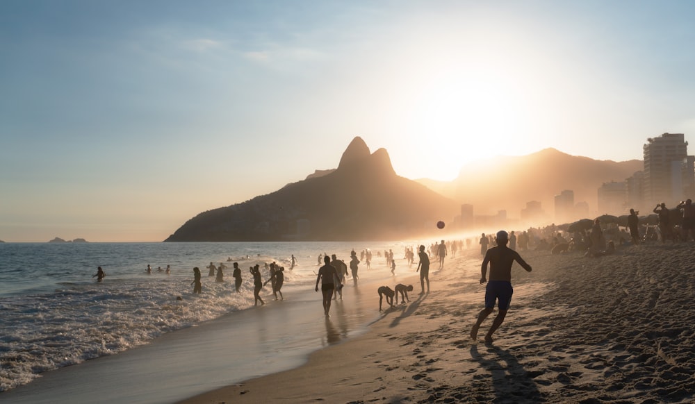 a group of people walking along a beach next to the ocean