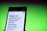 A smartphone screen displaying a webpage with large text about outlining a blog post for summer mocktail recipes. In the background, there is a pattern of horizontal green lines creating a vibrant backdrop.