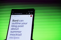 A smartphone screen displaying a webpage with large text about outlining a blog post for summer mocktail recipes. In the background, there is a pattern of horizontal green lines creating a vibrant backdrop.