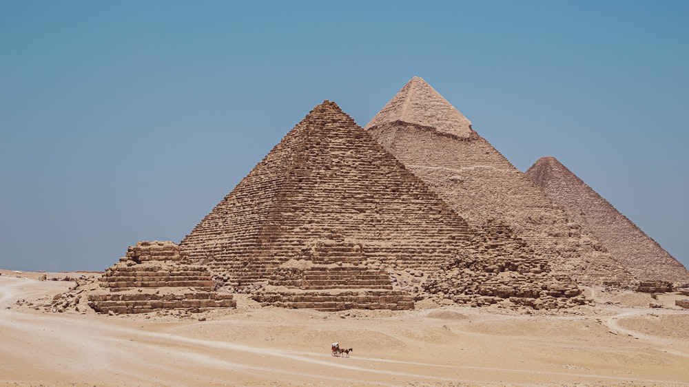 um grupo de pirâmides no deserto com um fundo do céu