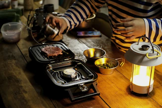 A joyful home cook sprinkling Saboréa seasoning over grilled vegetables on a sunny patio.