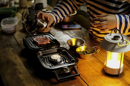 A joyful home cook sprinkling Saboréa seasoning over grilled vegetables on a sunny patio.
