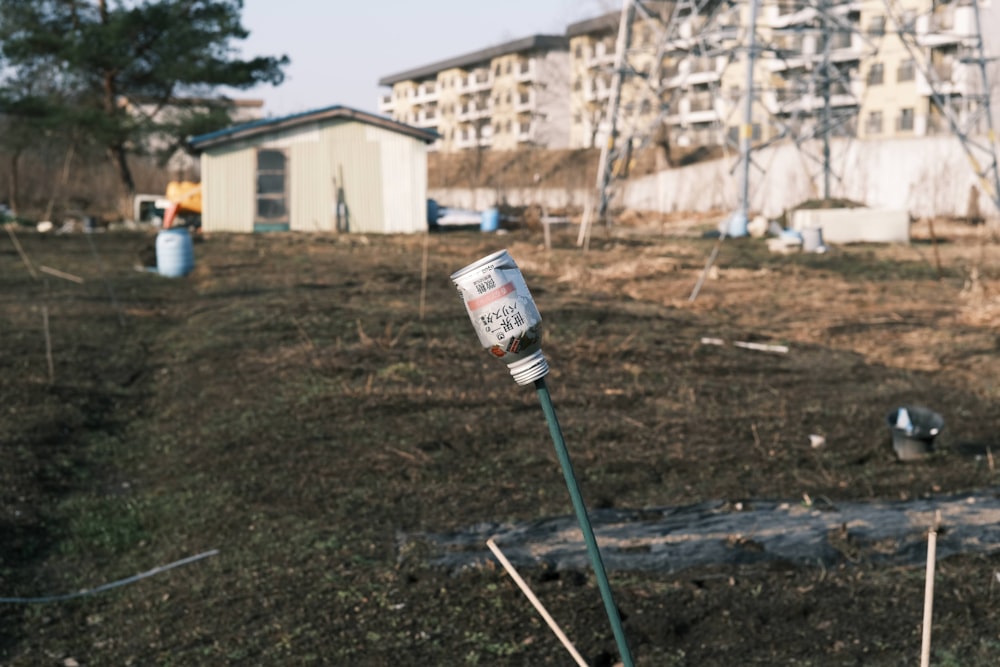 a parking meter in a field with a building in the background