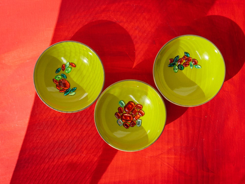 three yellow bowls sitting on top of a red table