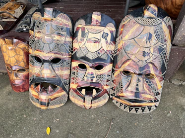 Close-up of handcrafted Myènè wooden masks displayed in a market.