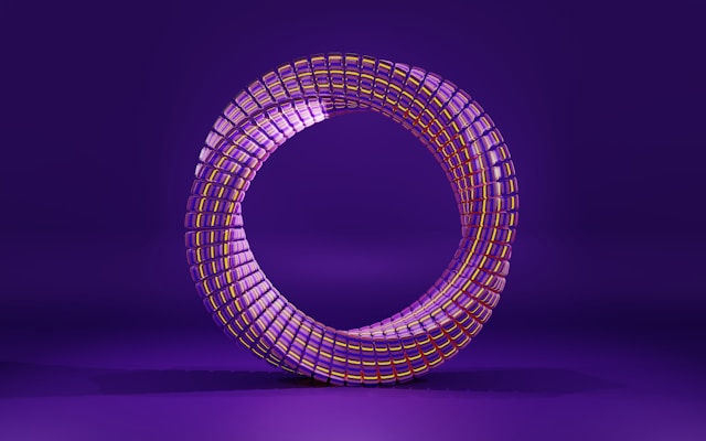 A vibrant, circular structure made of interlocking, reflective segments with a purple and yellow color scheme. It stands against a deep purple background, creating a futuristic and visually striking appearance.
