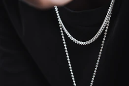 a person wearing a black shirt and a silver chain necklace