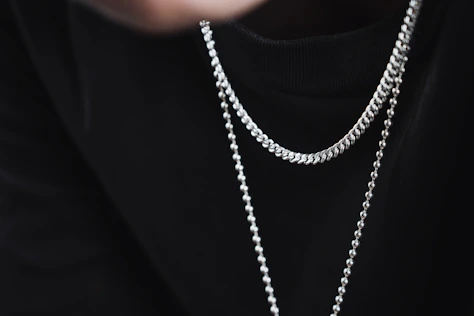 a person wearing a black shirt and a silver chain necklace