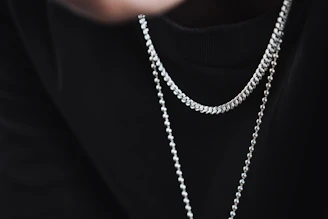 a person wearing a black shirt and a silver chain necklace