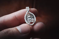 Detailed shot of a silver pendant with intricate taracea work, illuminated softly to highlight craftsmanship.