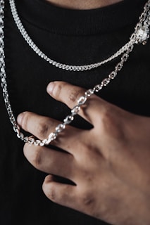 a person wearing a black shirt holding a silver chain