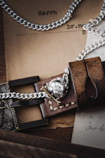 A close-up of leather cuffs and chains resting on a black surface, hinting at restraint and devotion.