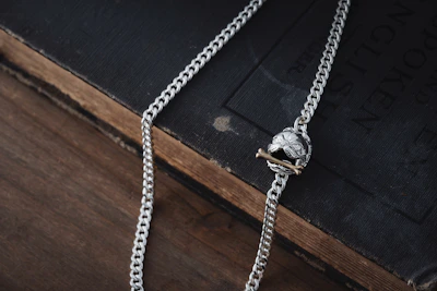 A delicate silver necklace draped over a vintage book.