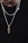A close-up view of two silver chains with pendants against a plain black background. One pendant is a gold, segmented piece, while the other is a silver heart. The chains have a shiny, polished appearance.