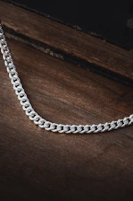 A sparkling silver necklace resting on a rustic wooden table.