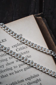 Close-up of broken chains lying on an open Bible with a bronze cross shining nearby.