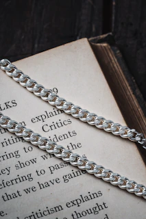 Close-up of broken chains lying on an open Bible with a bronze cross shining nearby.