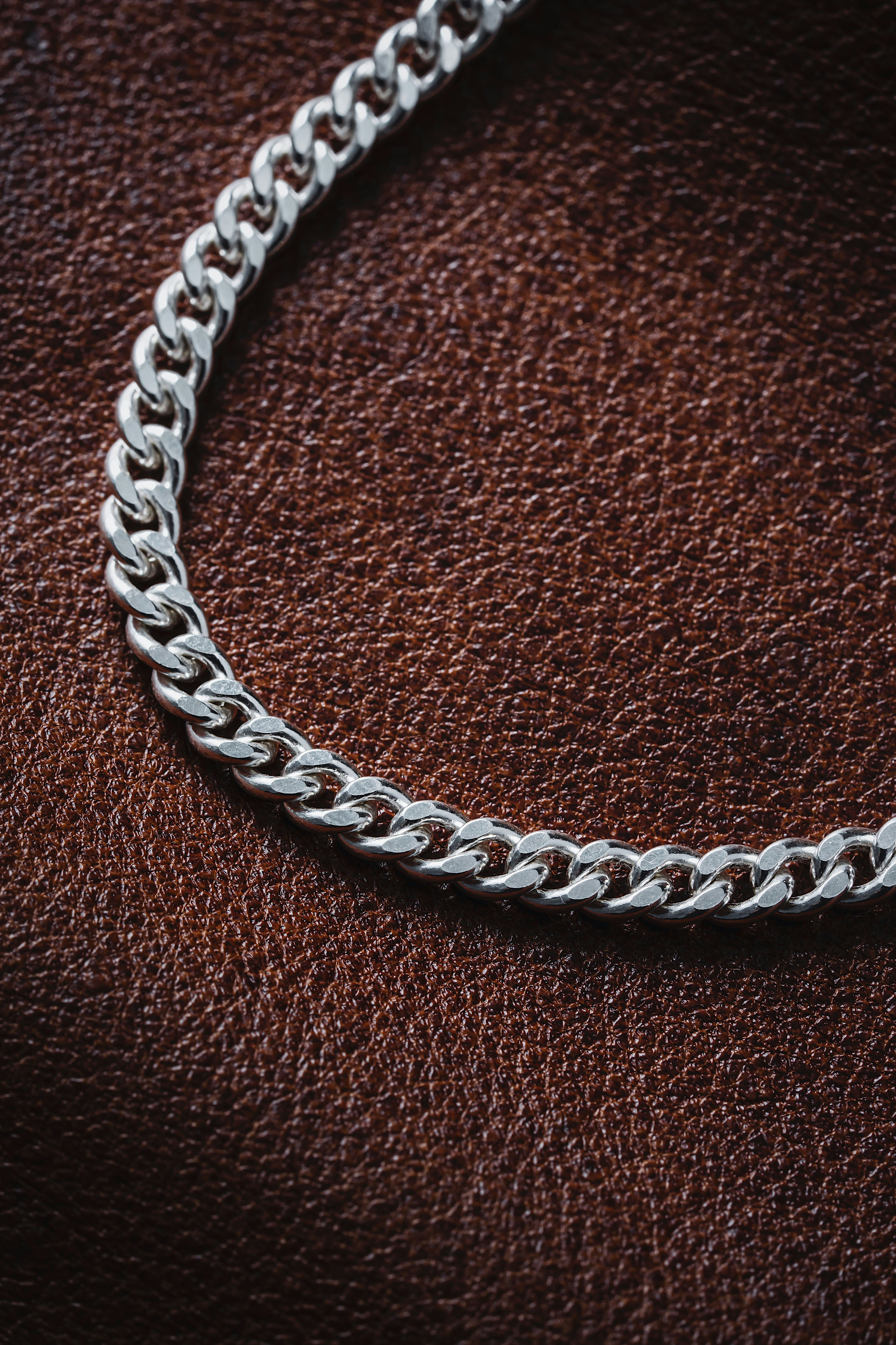 a silver chain on a brown leather surface