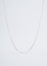 Close-up of a sleek black anti-tarnish necklace resting on a minimalist white surface.