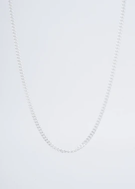 Close-up of a minimalist silver necklace resting on a sleek black velvet background.