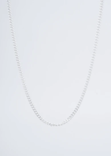 Close-up of a minimalist silver necklace resting on a sleek black velvet background.