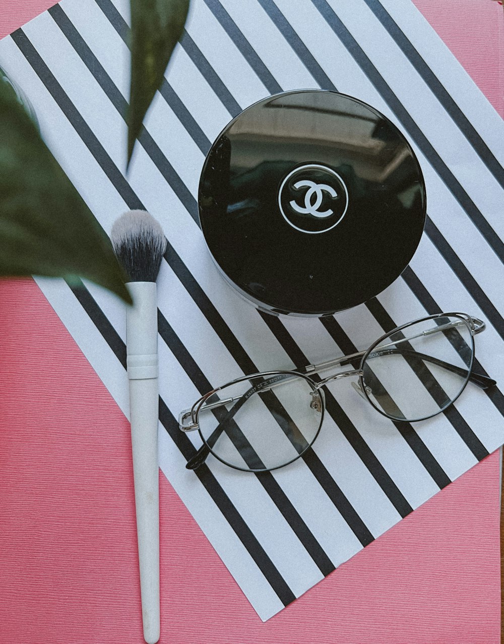 a pair of glasses and a brush on a pink and black background