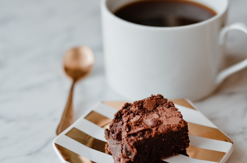 a piece of chocolate cake on a plate next to a cup of coffee