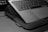 A laptop is positioned on a textured fabric case, partially open to reveal the keyboard. The image is in black and white, emphasizing the sleek design of the device. The environment appears minimalistic and professional.