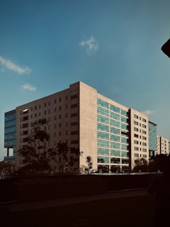 a tall white building sitting next to a lush green park