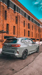 A sleek SUV parked at a bustling airport terminal under a bright blue sky.