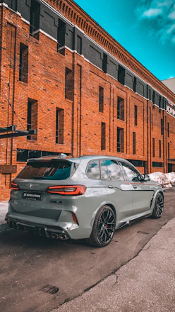 A sleek SUV parked at a bustling airport terminal under a bright blue sky.