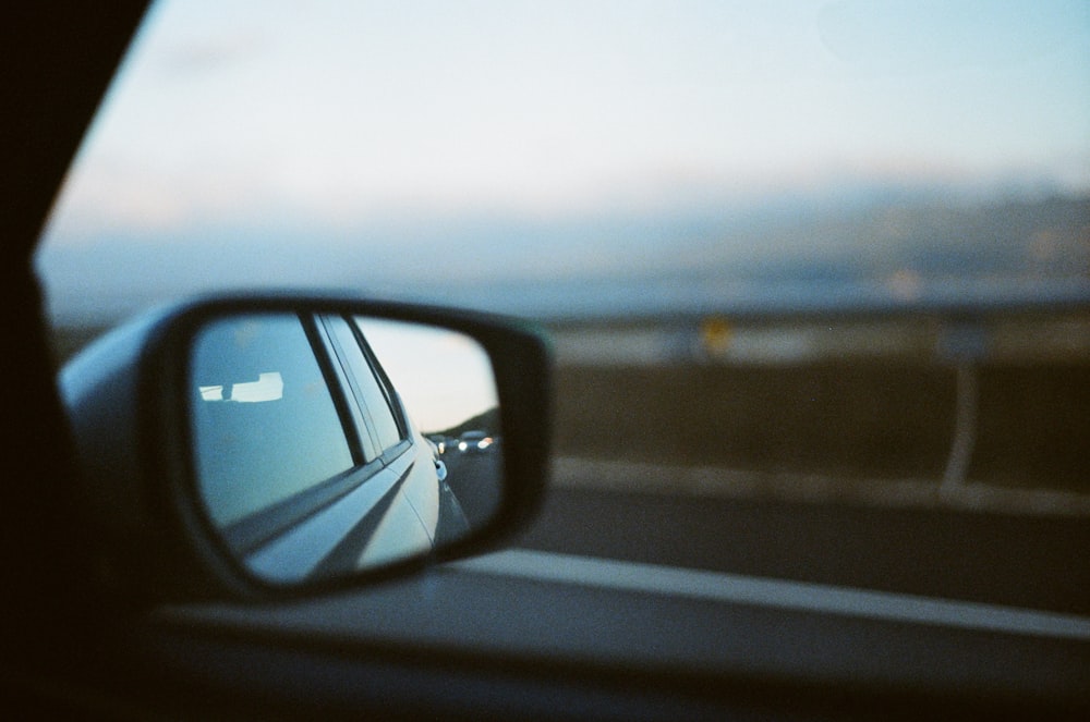 a car's side view mirror with a view of the ocean