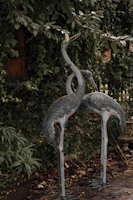 Antique iron ornamental statue nestled among lush garden greenery