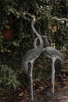 Antique iron ornamental statue nestled among lush garden greenery
