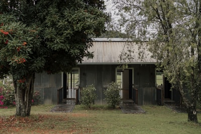 a small house with a metal roof in the middle of a field