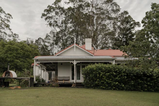 a white house with a red roof surrounded by trees