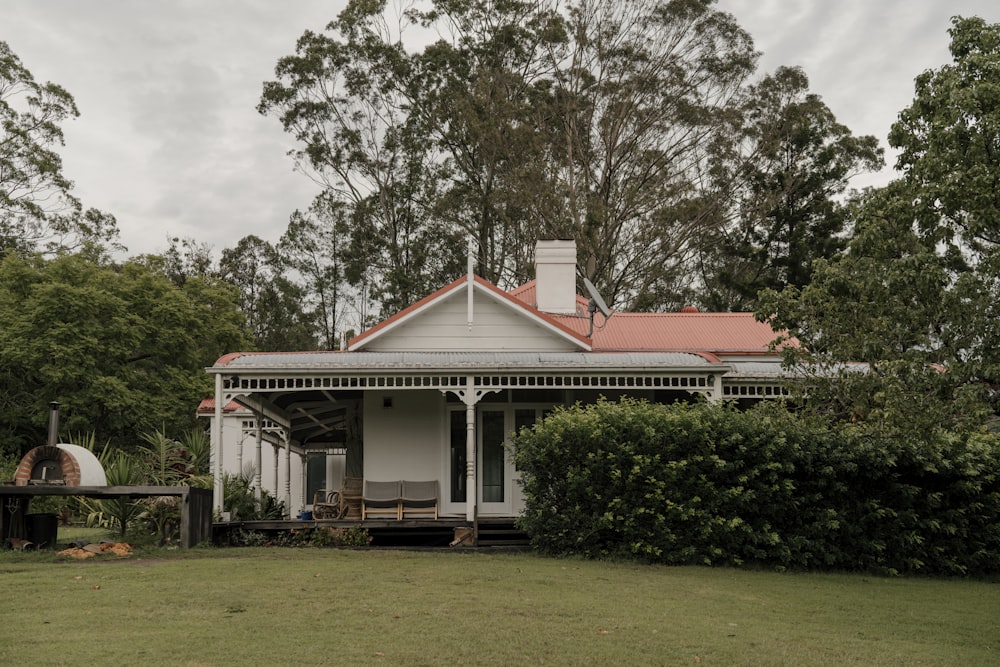 a white house with a red roof surrounded by trees